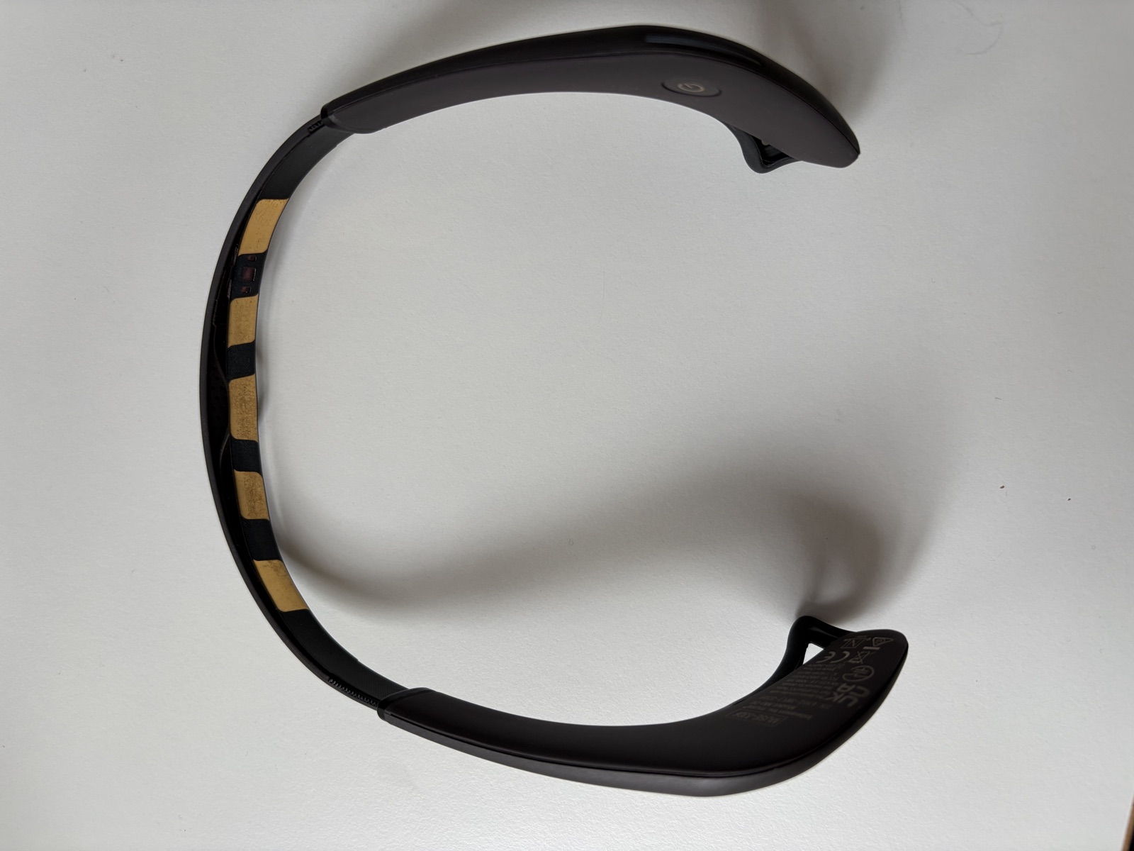 A Muse EEG headband lying on a desk, the gold sensor strip visible along the inside of the band